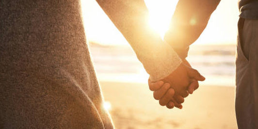 Rearview shot of an unrecognizable couple holding hands while at the beach